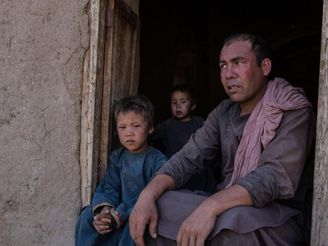 Man sits in the doorway with his two children