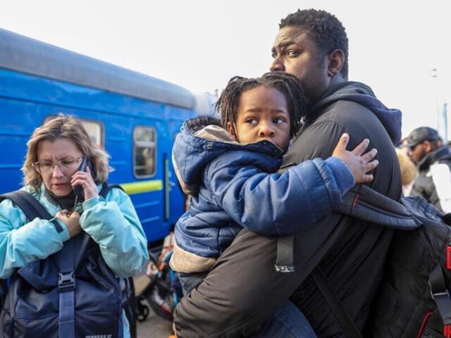 A man holding a child and standing by a train