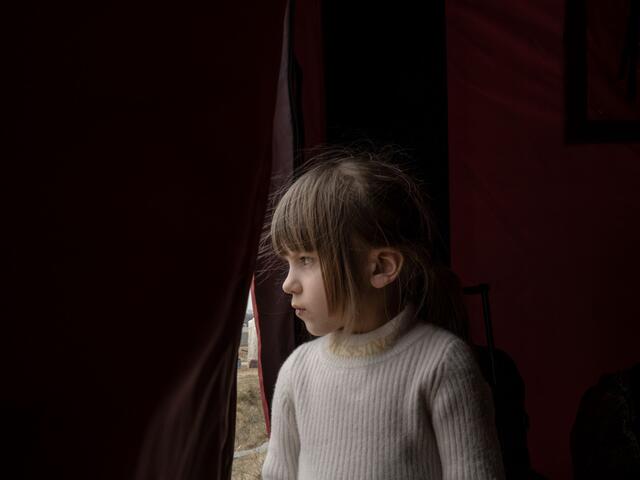 A young girl looking out of a tent