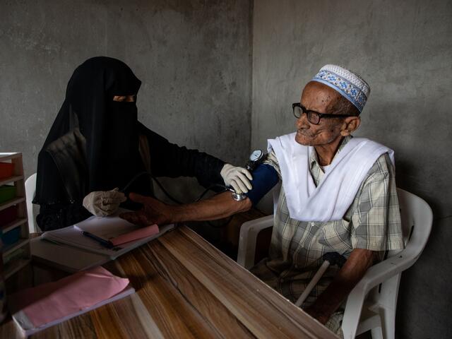 A woman takes the blood pressure of a patient