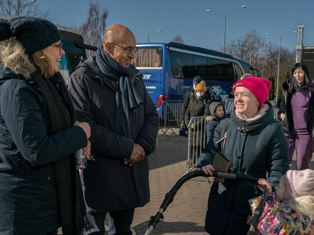 A group of people speaking in front of a bus.