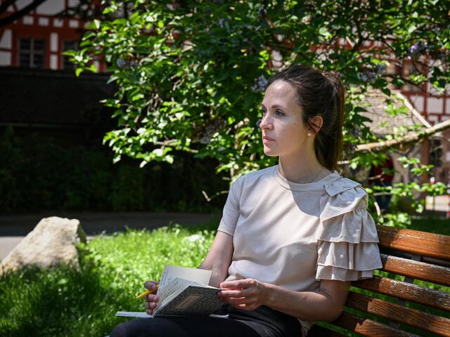 A woman sitting on a bench with a book in her hands