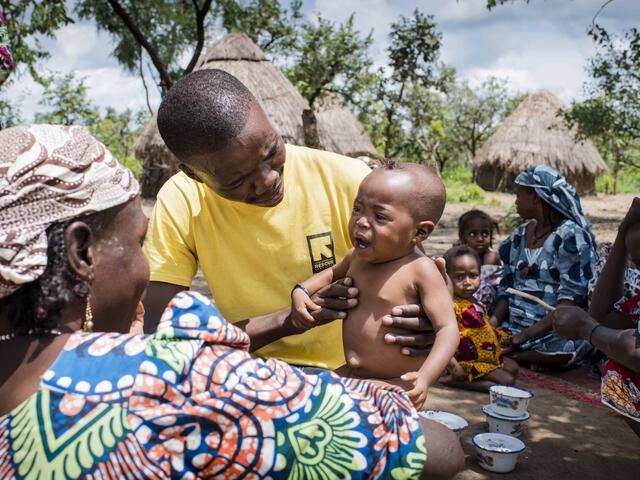 An IRC health worker examines a young child suffering from malnutrition as people return to their village after fleeing fighting. 