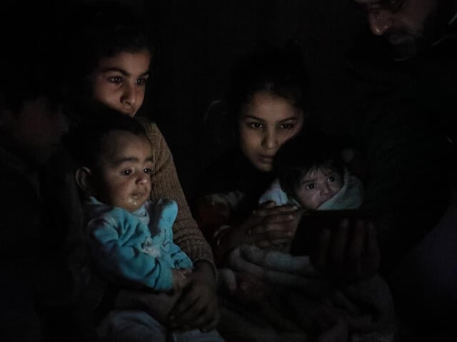 A family huddles in the dark in their basement shelter in East Ghouta, Syria
