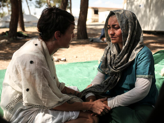 Lena Headey holds hands as she sits and speaks with a woman who is now a refugee from Afghanistan