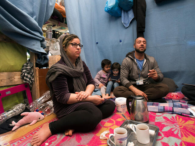 A family sits on the ground in a tent in Moria refugee camp on the island of Lesbos in Greece