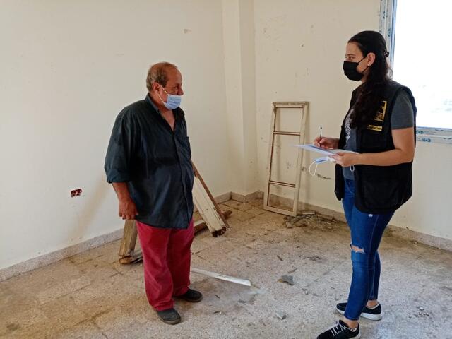 Assad speaks with an IRC staff member in his home amid repairs needed after the Beirut explosion.