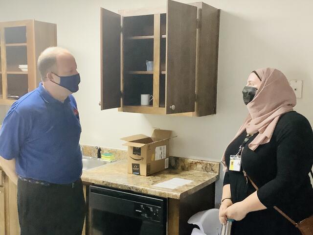 Colorado governor Jared Polis an an Afghan refugee woman speak in the kitchen of the woman's new apartment.