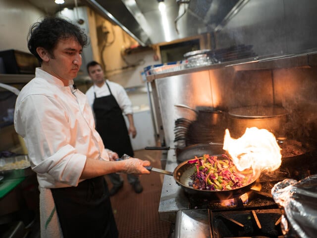 A chef from Afghanistan sautees vegetables in a skillet over a high flame at his restaurant in Virginia. 