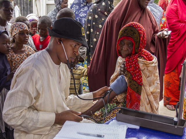 An IRC health worker checks the blood pressure of an elderly woman in an area where people have fled Boko Haram violence.