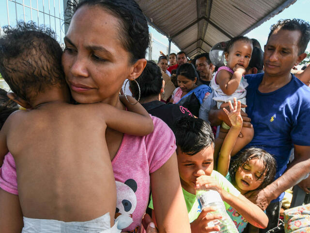 A Honduran migrant couple and their five kids taking part in a caravan heading to the U.S., wait to cross the border from Guatemala to Mexico