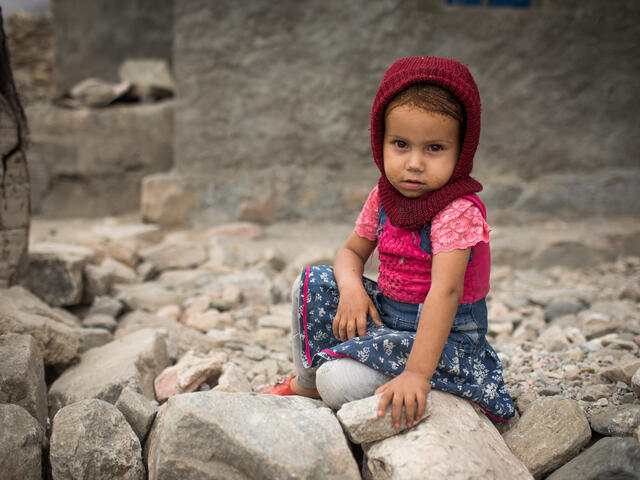 A young girl sits on the ground in a village in Yemen