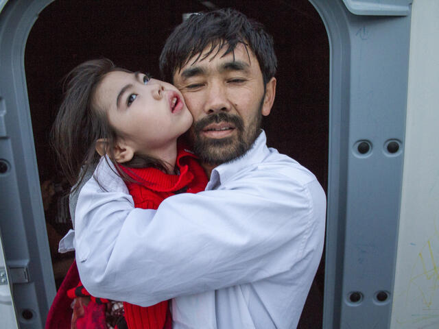 Afghan refugee father holds his daughter.