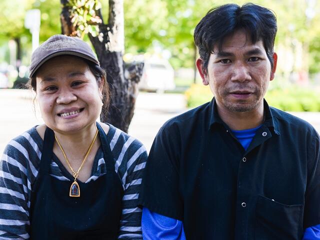 Store owners standing together outside of their restaurant.