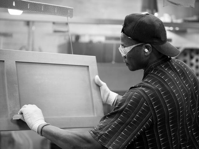 A man sanding window frames in a factory.