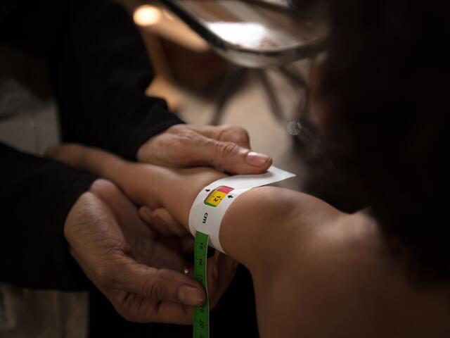 An IRC health worker measures a child's upper arm with MUAC tape to check for signs of acute malnutrition. 