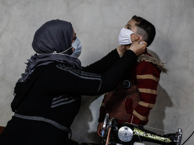Um Abdo fits a mask on one of her young sons in northwestern Syria.