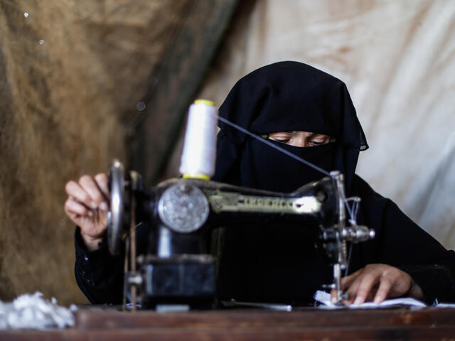 Wa'ad sews COVID-19 masks on a sewing machine in her makeshift shelter in northwestern Syria.