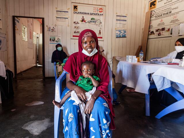 Farhiyo Abukar sits in a chair in the IRC clinic with her son on her lap. 