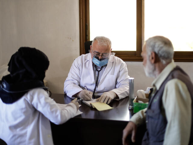 A doctor sits at his desk at a clinic run by the IRC in Idlib. He wears a face mask to protect the staff and patient he is speaking with from COVID-19.