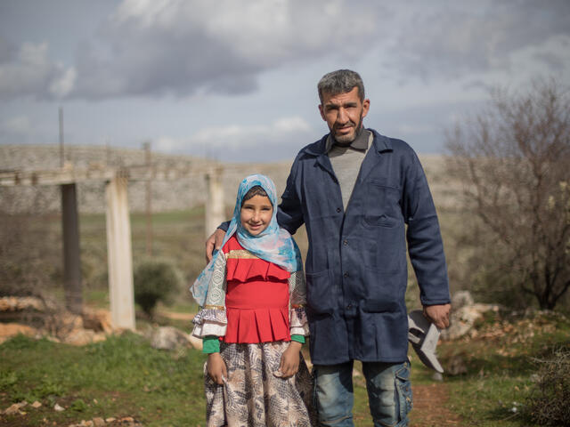 Sara and her father, Emad, stand outside. He has his arm around her and they are both looking at the camera. 