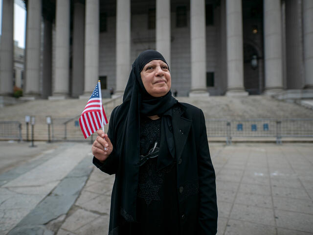 Maha al-Obaidi stands in front of the federal court house while holding a flag
