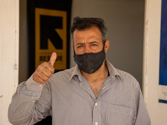 yrian man standing outside an IRC clinic in Zaatari refugee camp gives a thumb's up sign after receiving a COVID-19 shot