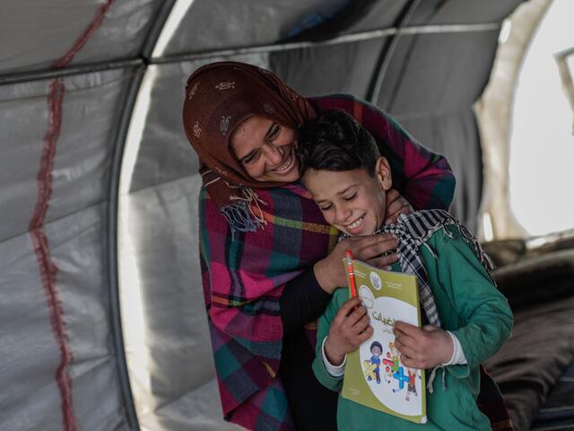 Sundus stands behind her son Omar. They are both laughing. 