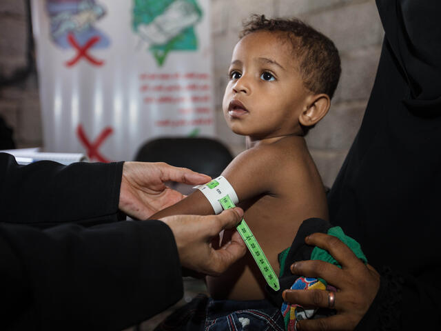 A health worker measures Nabiha's toddler son's upper arm at the IRC clinic in Yemen where he was treated, finding he no longer sufferes from malnutrition.