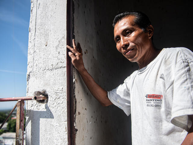 Reynaldo stands leaning against the doorway of a church he is painting in Zacatecoluca, El Salvador.