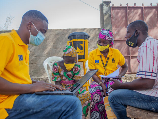 Anastasie sits outdoors at an IRC Safe Space with IRC staff 