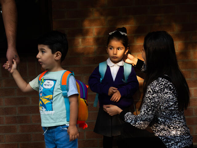 Hiba crouches next to her 4-year-old daughter Hiba to say goodbye as she gets ready to join her brother going to school.