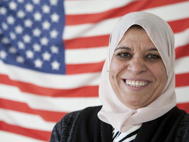 New American citizen stands in front of American flag