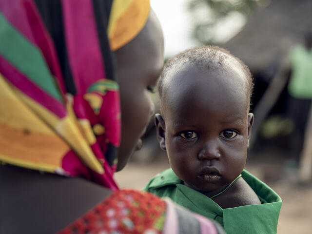 Close up of a mother facing away from the camera while her baby faces toward the camera. 