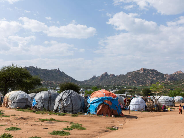 A landscape photo of tents with mountains in the distance. 