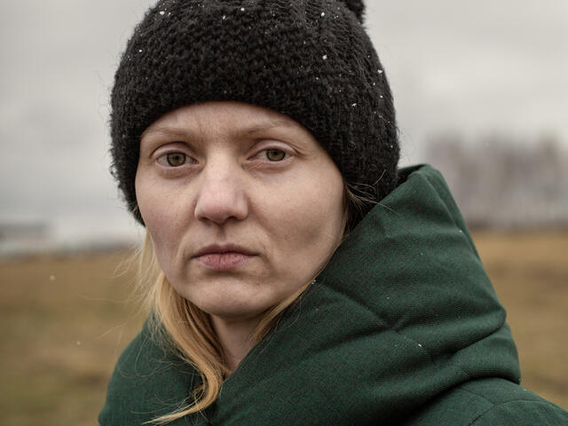A portrait of Victoria, a refugee from Ukraine. She is wearing a winter coat and hat. 