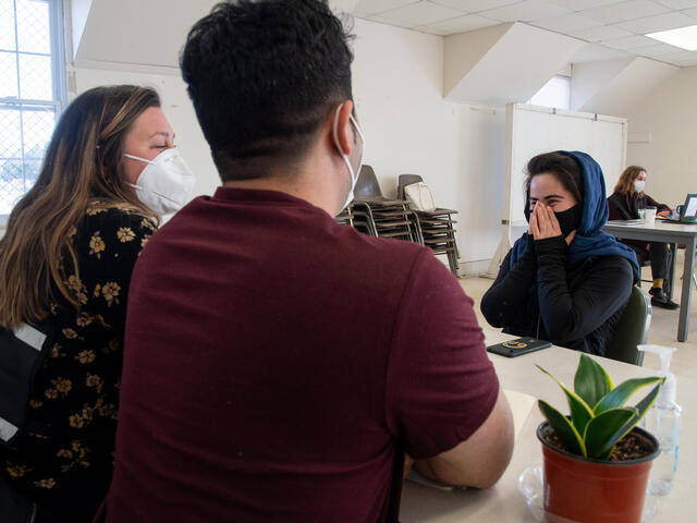 Belqisa sits at a table across from two IRC staff members 