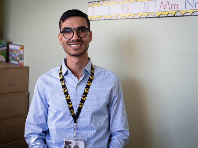 A portriat of Shir Zad in the IRC office. He is wearing a button down shirt, glasses and an IRC lanyard, and is smiling.