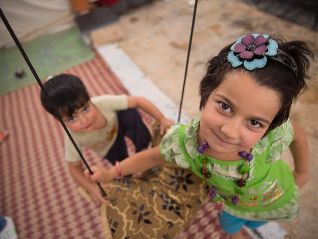 Syrian children play outside of their makeshift home in a Jordan