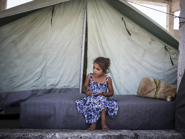 Seven-year-old sits outside her family's tent in the Alexandria refugee camp