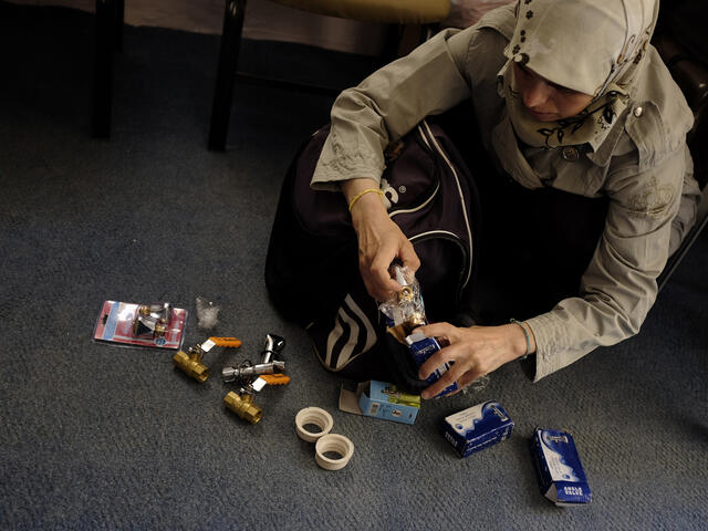 Syrian woman plumber organizes parts to fix a leak