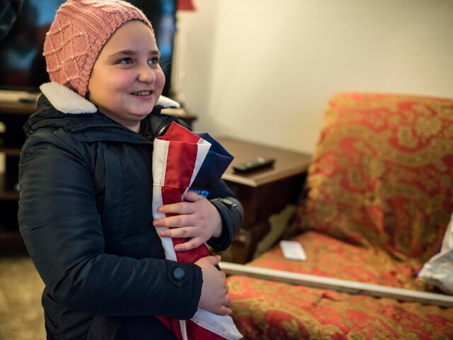 11-year-old Alaa holds a folded American flag.