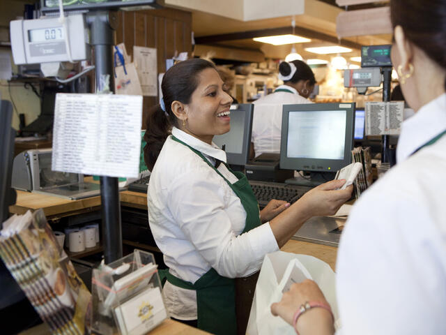 Uma rings up a customer at a gourmet market 