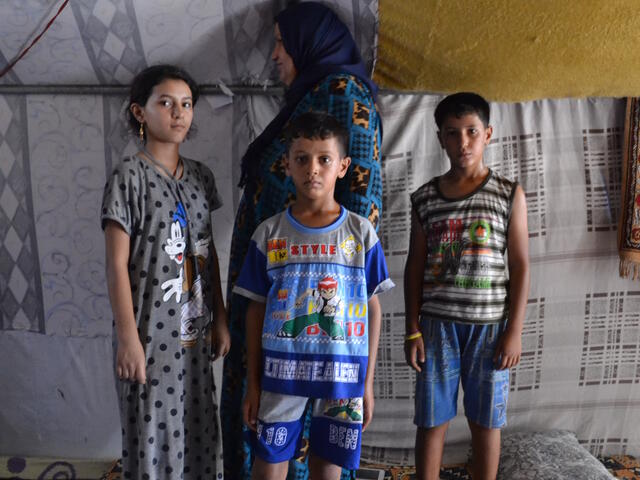 Abeer with her three children inside a tent in the camp near Baghdad