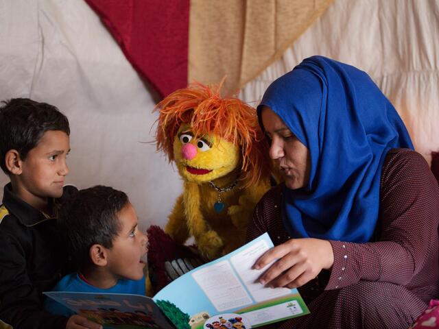 Syrian mother reads with her sons and a Sesame Street Muppet Tonton