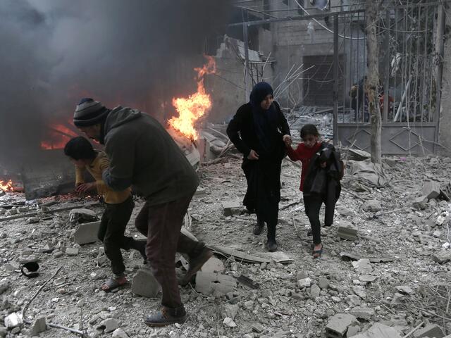 Syrian civilians run for cover after a bomb hits Eastern Ghouta in the suburbs of Damascus.