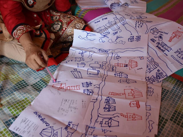 An aid worker uses a map of the refugee camp to indicate areas at risk of flooding or landslides during the monsoon rains.