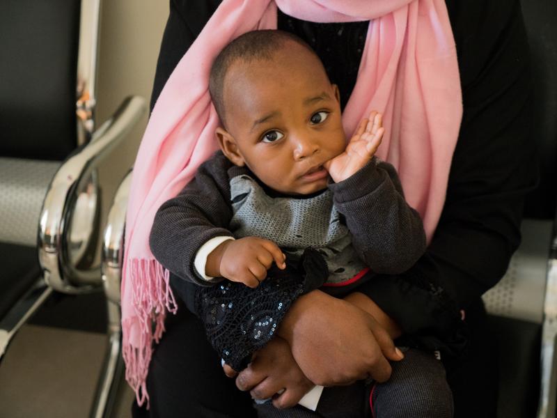 Khal, a 10-month-old boy from Eritrea, sits on his mother's lap 