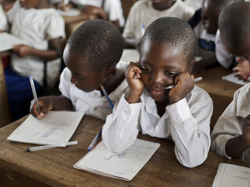 A little boy and his classmates work on assignments in a classroom in North Kivu, Democratic Republic of Congo
