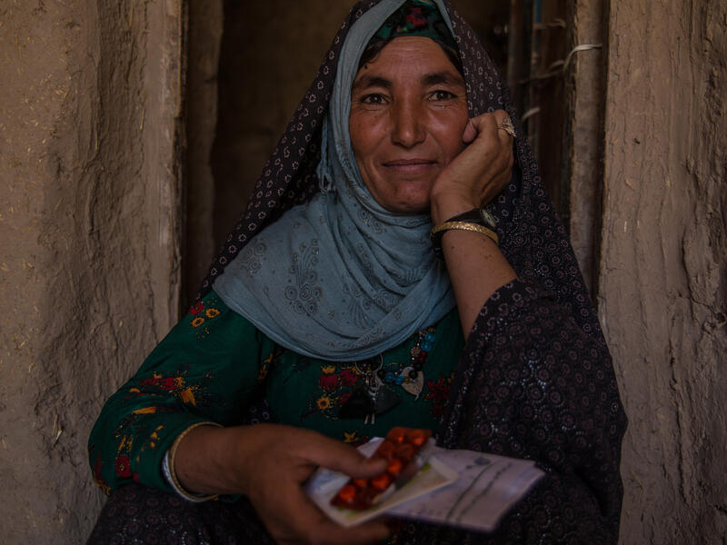 Dunya Gul, 35, a widow from Kandihar, Afghanistan An Afghan woman sits in a doorway holding medicine and prescriptions from the IRC as part of its Afghanistan crisis response.